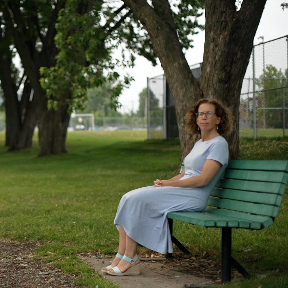 Isabelle Langlois assise sur un banc de parc.