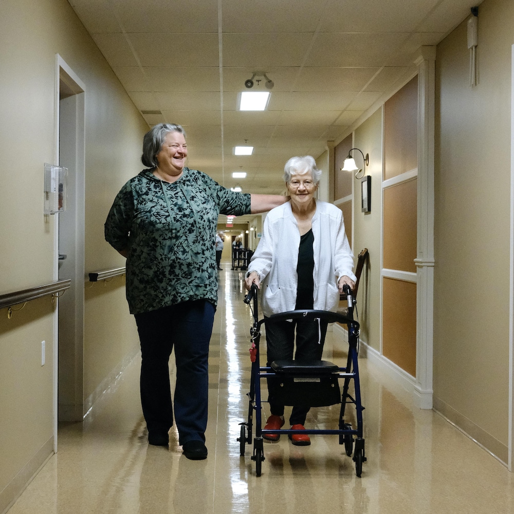 Isabelle Morasse et Rollande Camirand-Morasse marchent dans un couloir d'une résidence pour aînés.