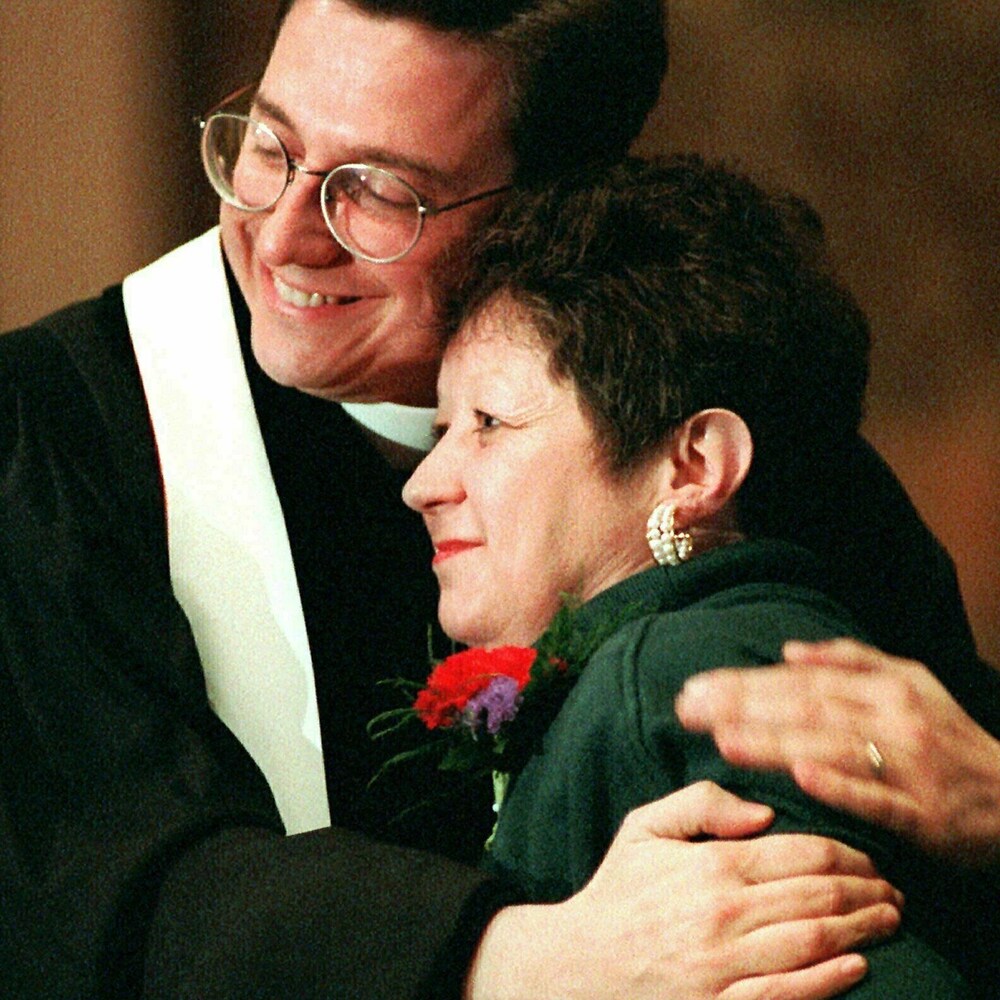 There was a man wearing a cassock holding a woman in his arms. 