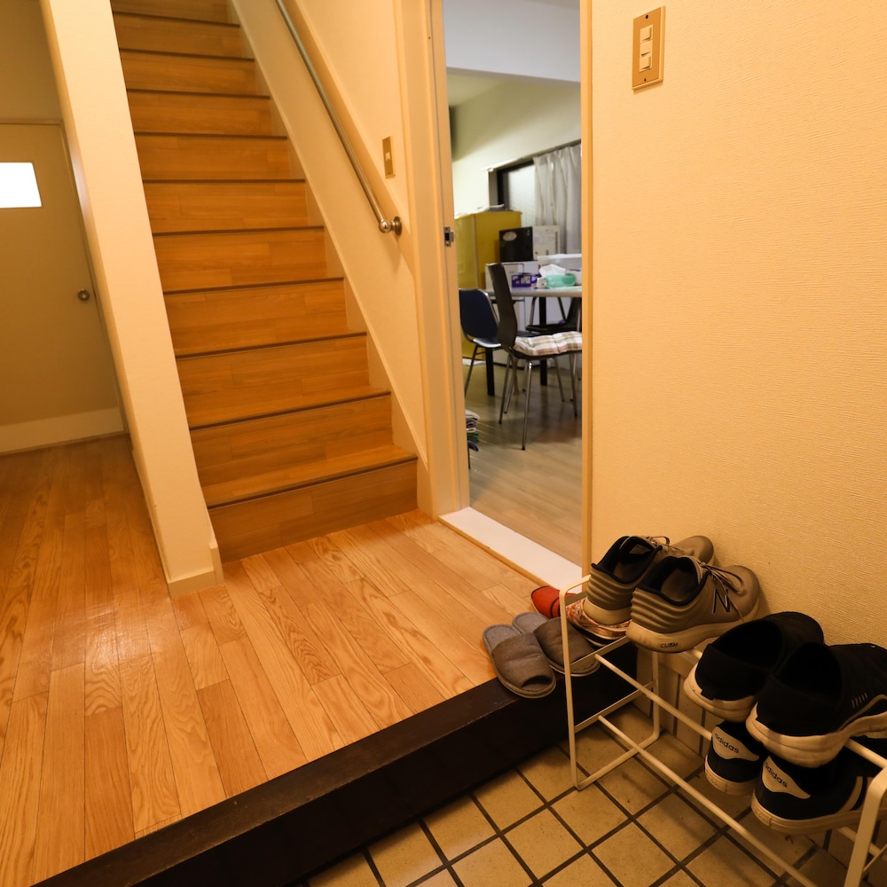 Une entrée d'appartement où sont posés trois pairs de souliers.