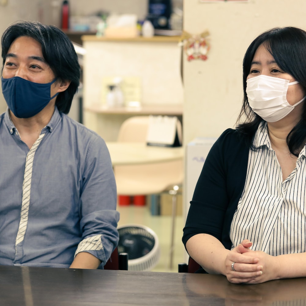 Kenji et Mary Kuze assis à une table. Ils portent des masques de tissu.