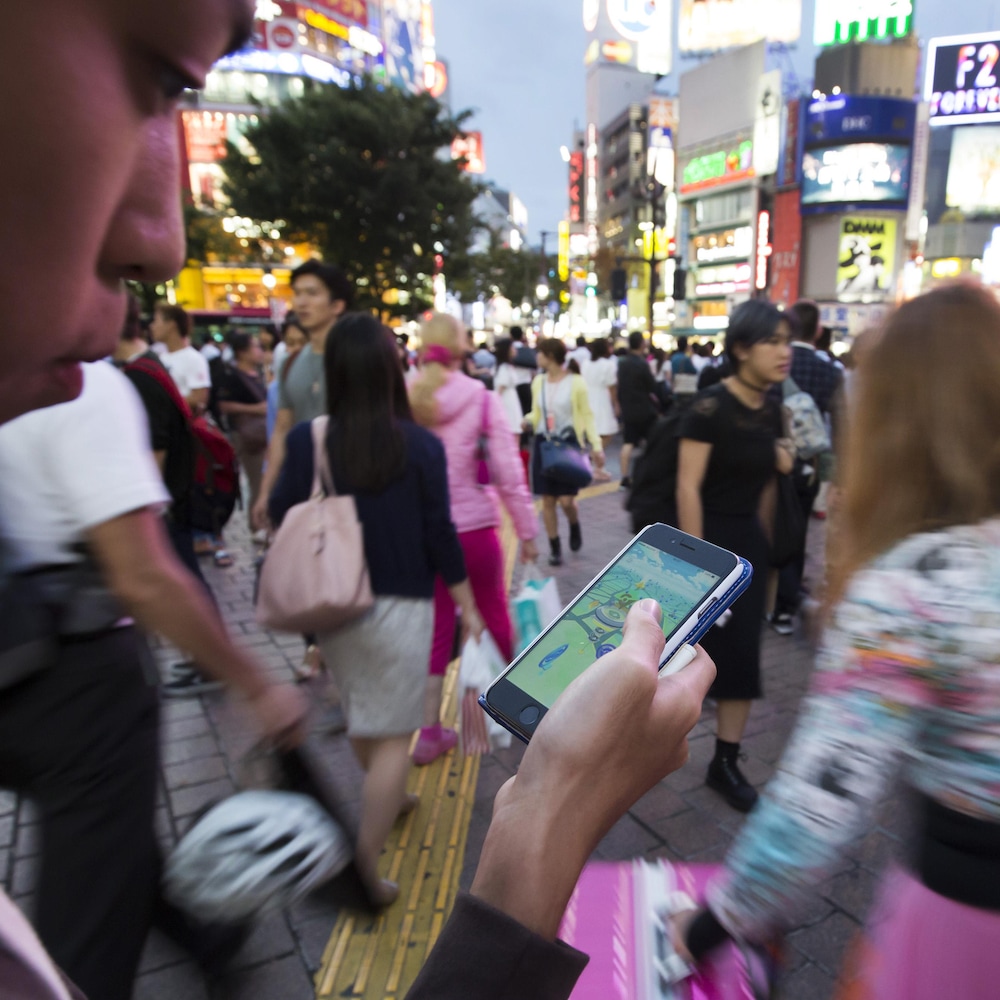 Une personne regarde son cellulaire dans une rue bondée de Tokyo.