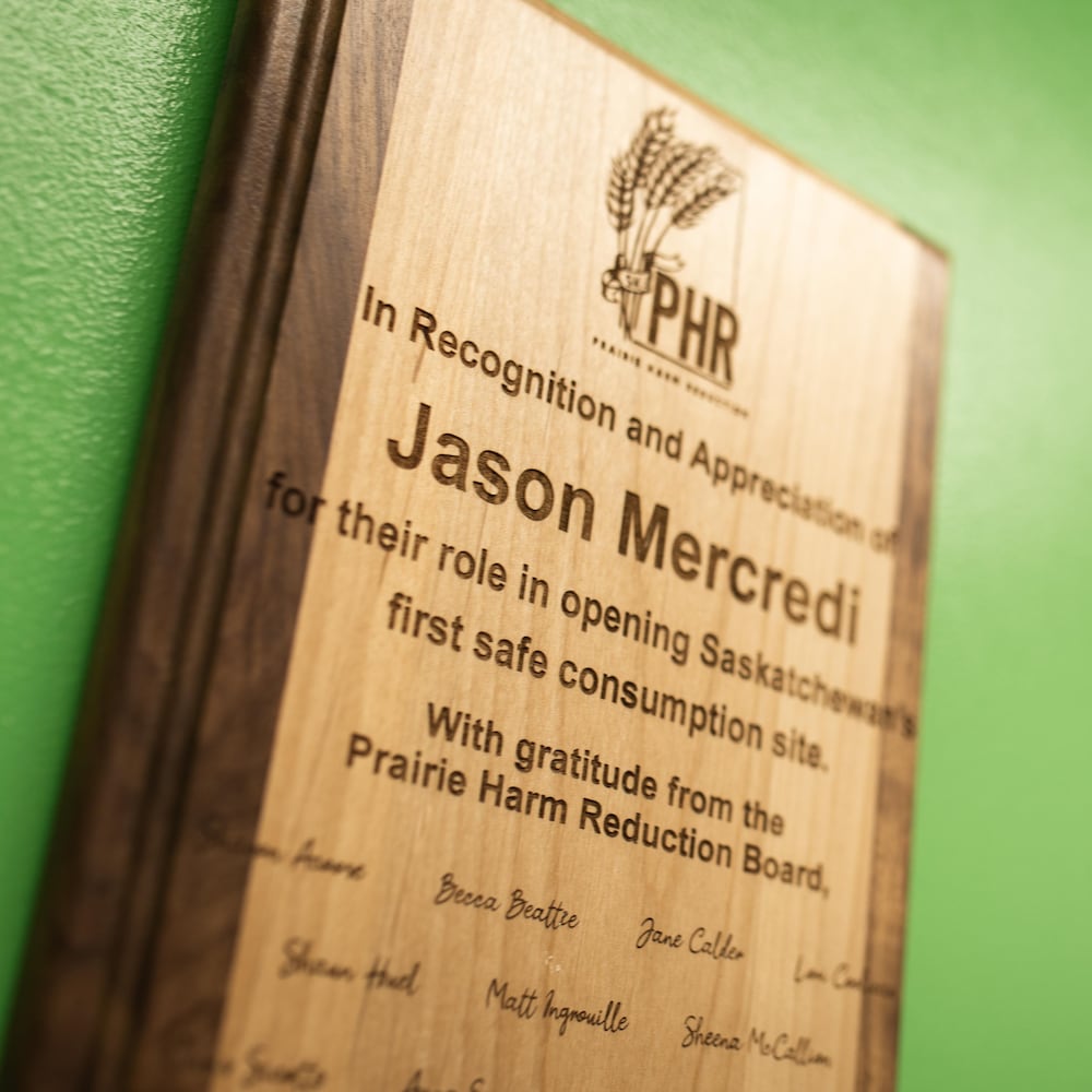 Un certificat au nom de Jason Mercredi affiché sur un mur vert à côté d'un cadre. 