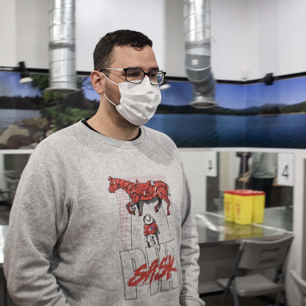 Jason portant un masque chirurgical est debout dans une salle de l'organisme Prairie Harm Reduction. 