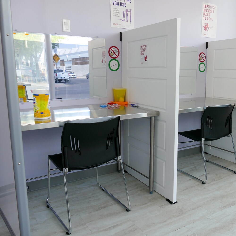 Des îlots avec des tables et des chaises sont installés dans un service de consommation supervisée. 