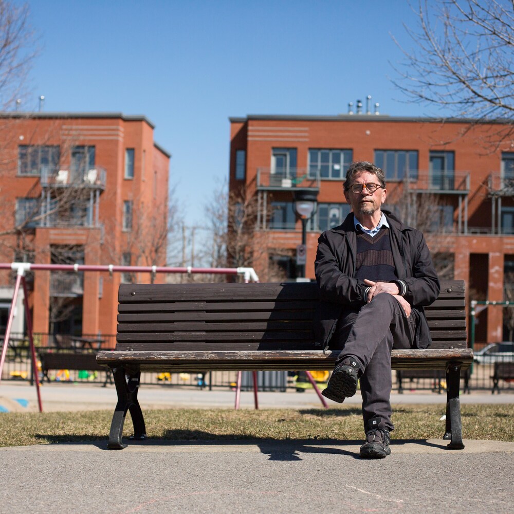 Jean-Marc Bougie pose assis sur un banc de parc.