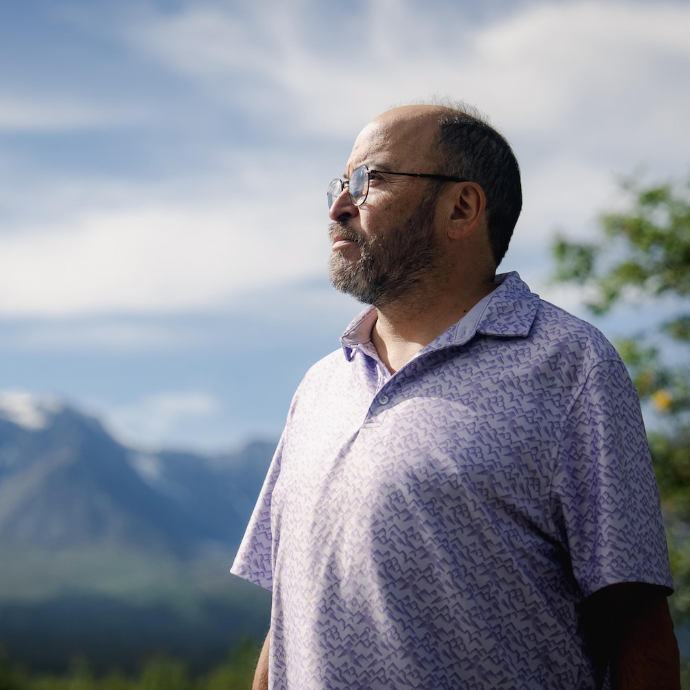 John Fingland regarde dans la distance, dans les montagnes au Yukon, en août 2026.