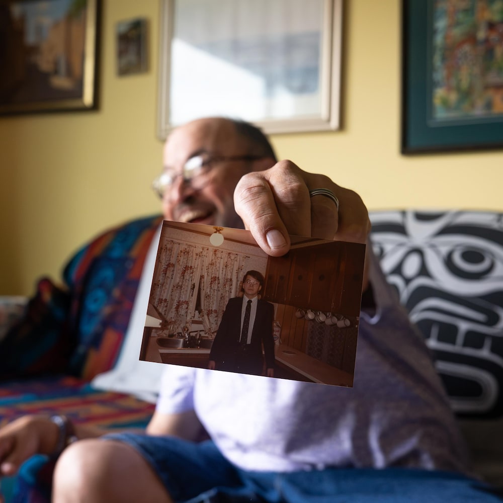 John Fingland tient une ancienne photo de lui, dans sa maison dans le hameau de Champagne, au Yukon, en août 2026.