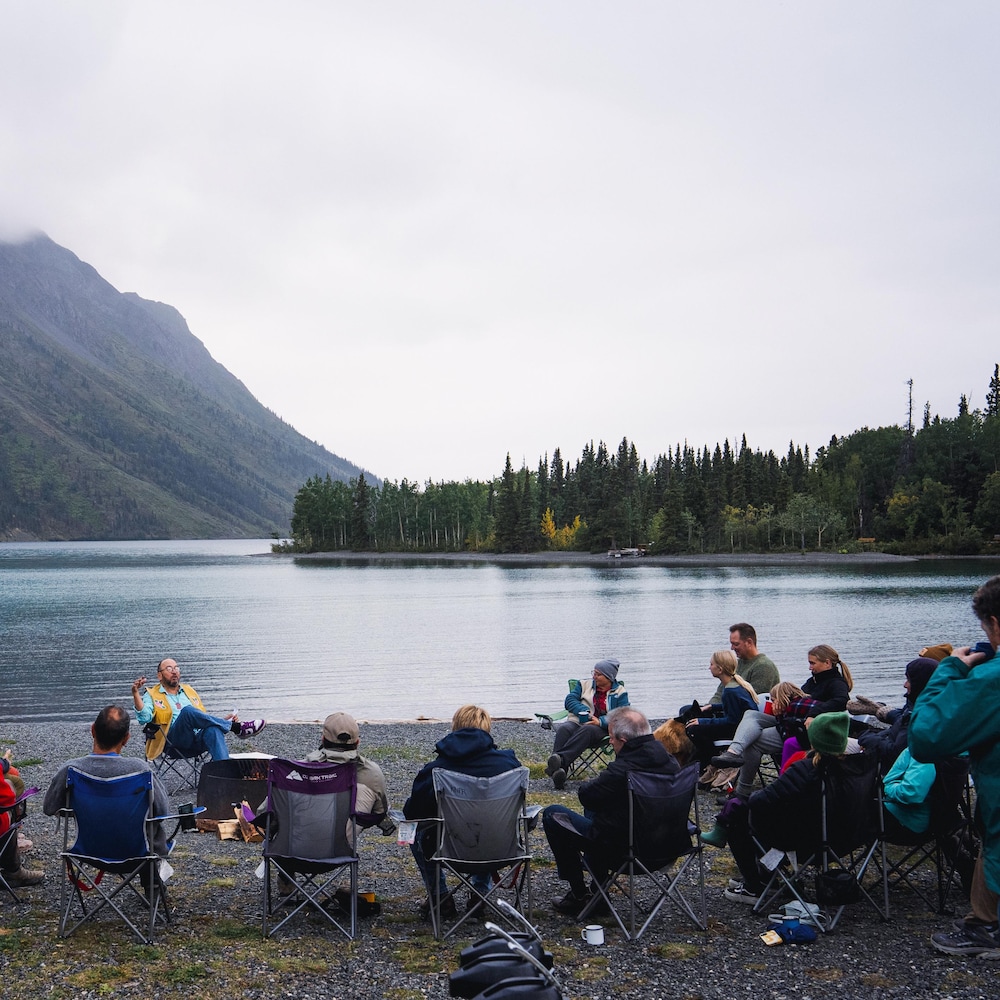 John Fingland raconte devant une groupe de personnes au bord du lac Kathleen, au Yukon, en août 2026.