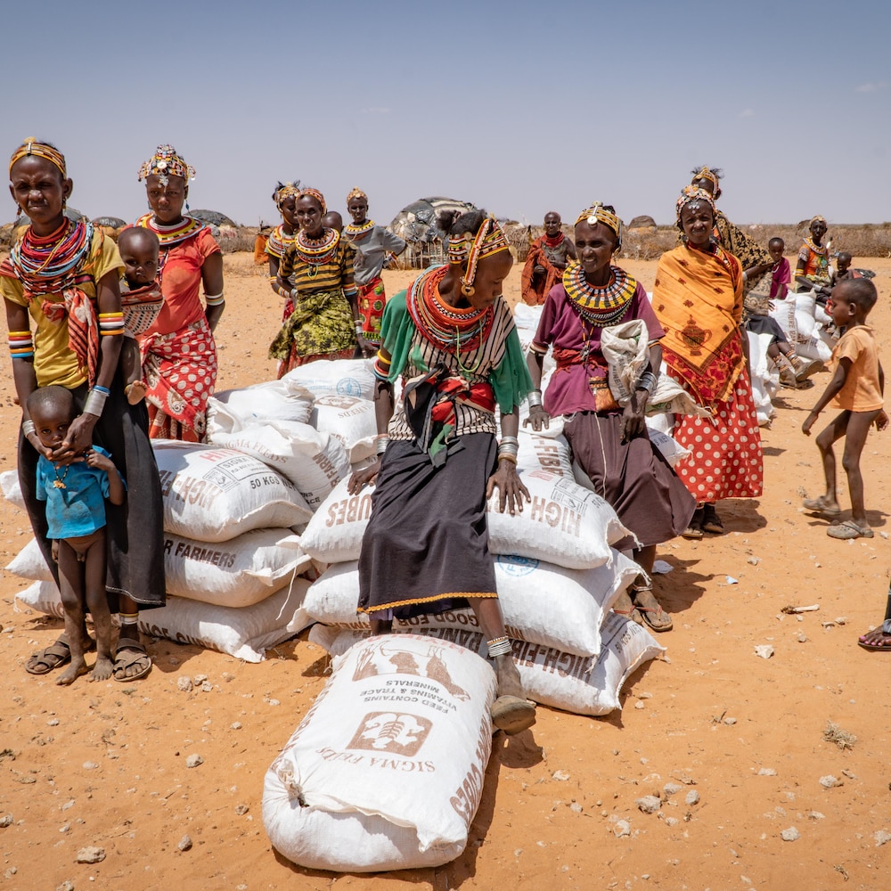 Des sacs empilés par terre et un attroupement de personnes.
