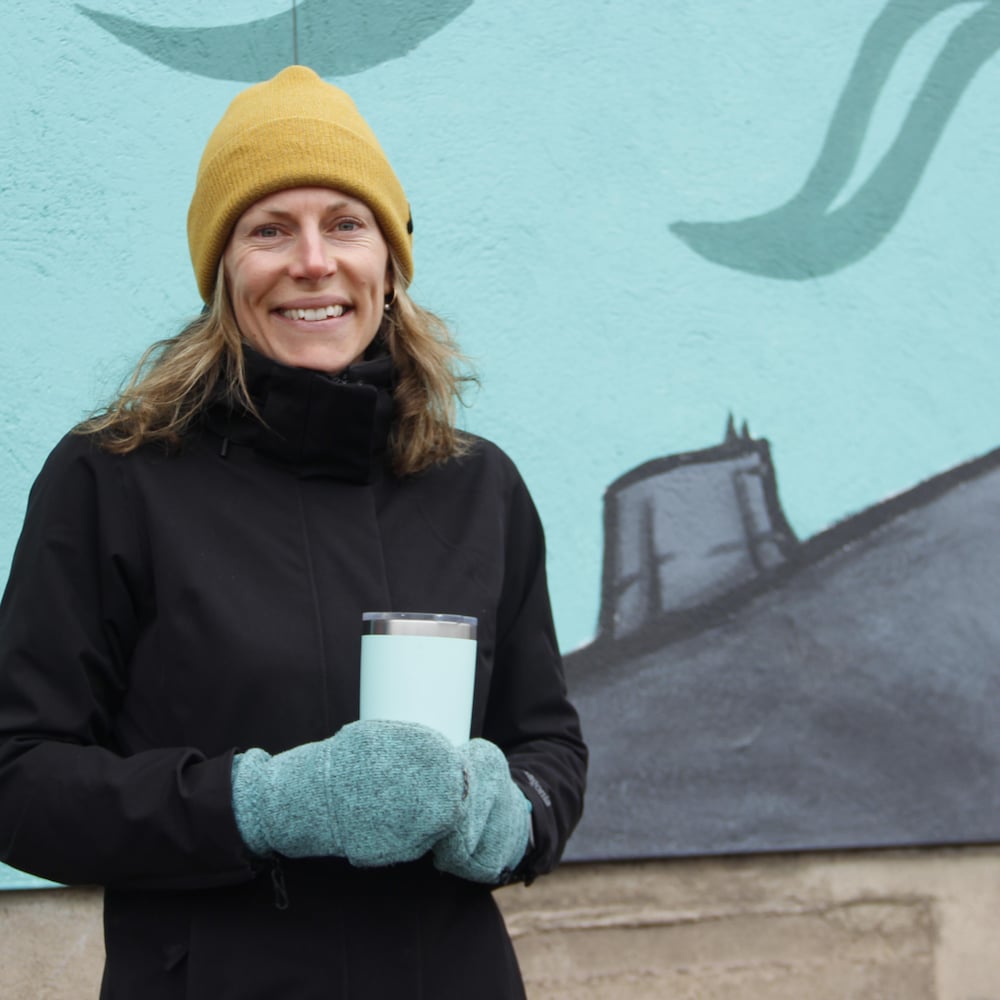 Kira Hoffman devant une murale, tenant son café en main.