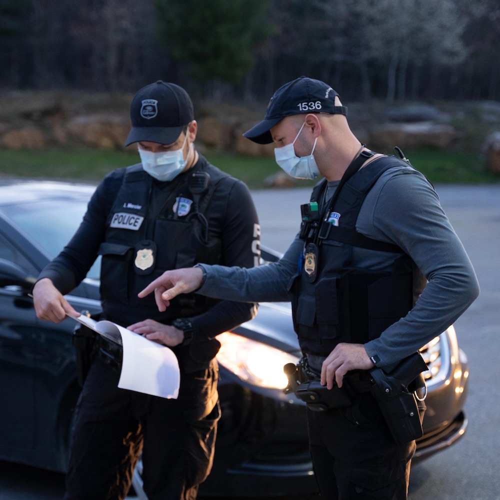 Deux policiers vêtus de gilets pare-balles regardent une feuille.