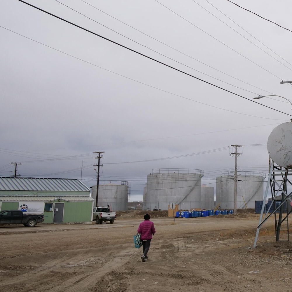 Une rue de Cambridge Bay avec une personne qui marche et un bâtiment avec une fresque, en septembre 2022.