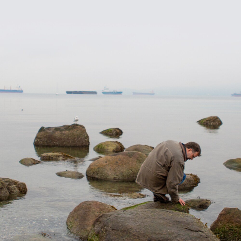 Christopher Harley est accroupi sur un rocher dans une baie proche de Vancouver, en Colombie-Britannique, en novembre 2022. 