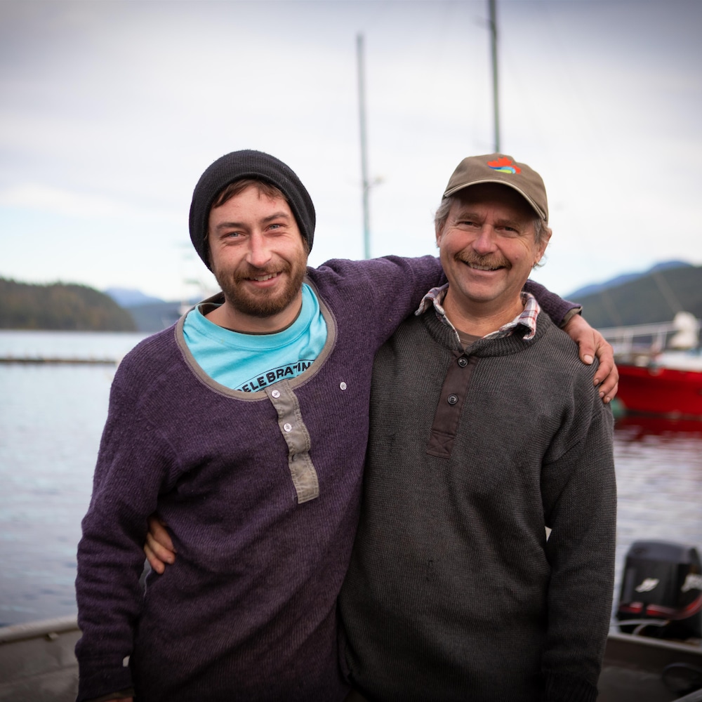 Sébastien et Yves Perreault qui posent, bras dessus, bras dessous, devant la baie de Okeover, en Colombie-Britannique, en novembre 2022.