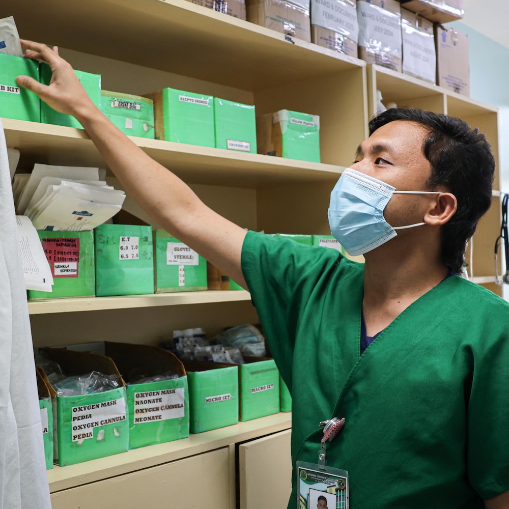 Joseph Matthew en tenue d'infirmier avec un masque, dans une salle d'hôpital pour le personnel infirmier, à Manille, aux Philippines, en mai 2025.