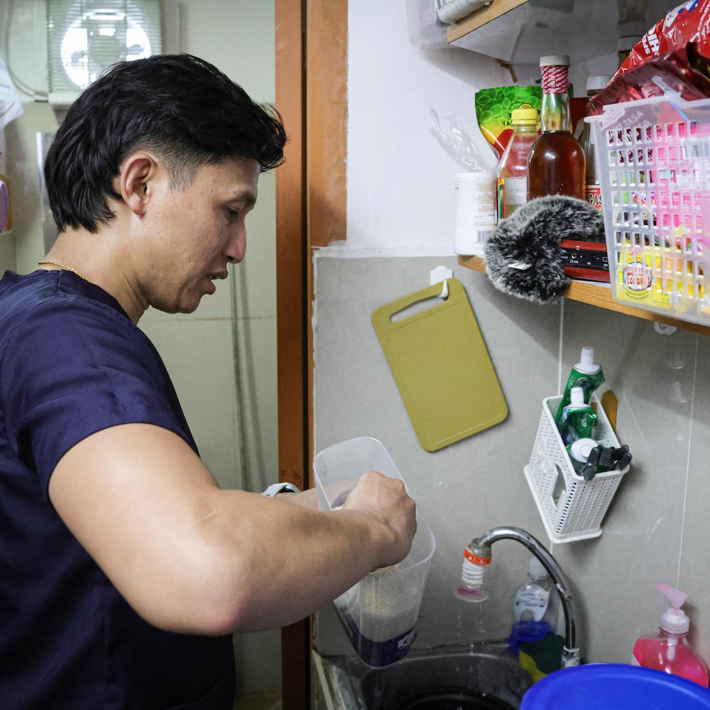 Nicolito Oba est en train de se servir du riz dans une toute petite cuisine, aux Philippines, en mai 2025.