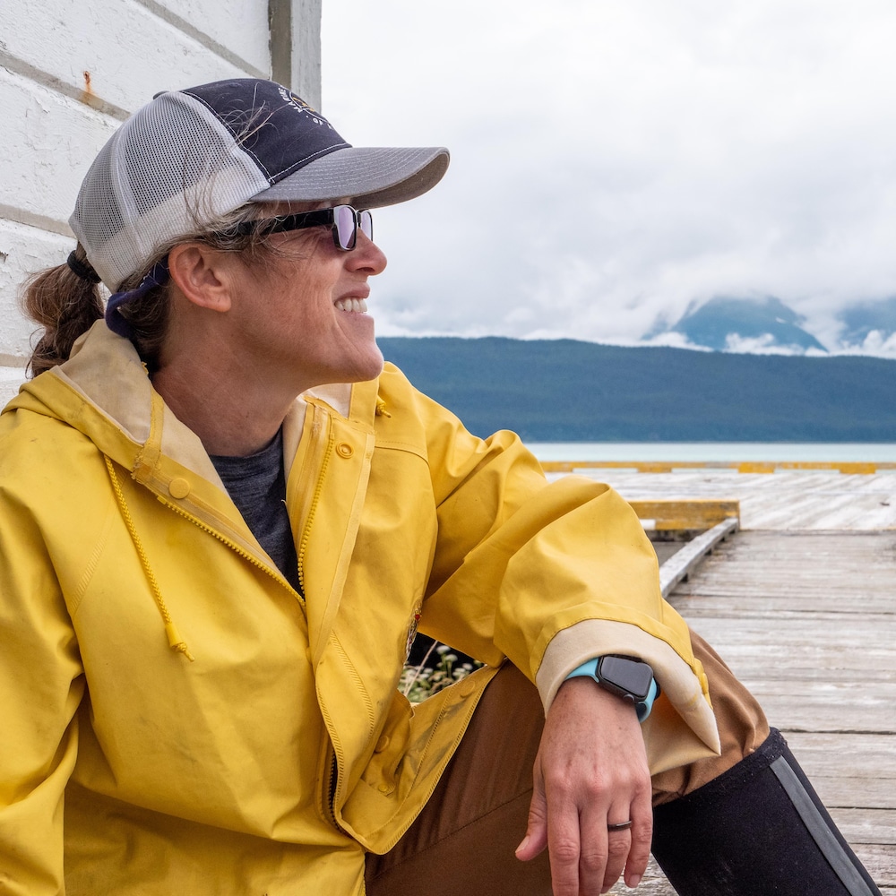 Portrait de Sue York assise sur le pourtour du phare avec l'océan en fond en Alaska, juillet 2022.