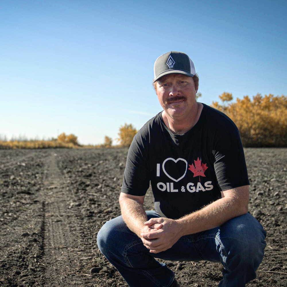 Kevin Heck squats in a plowed field in the Alberta prairie near Frog Lake in October 2022.
