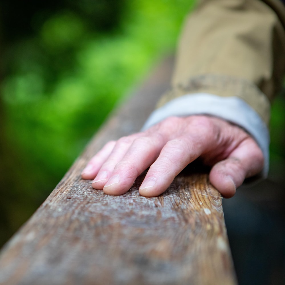 La main d'une personne posée sur une barrière en bois dans le parc provincial Chun T'oh Whudujut, en Colombie-Britannique, en juin 2022.