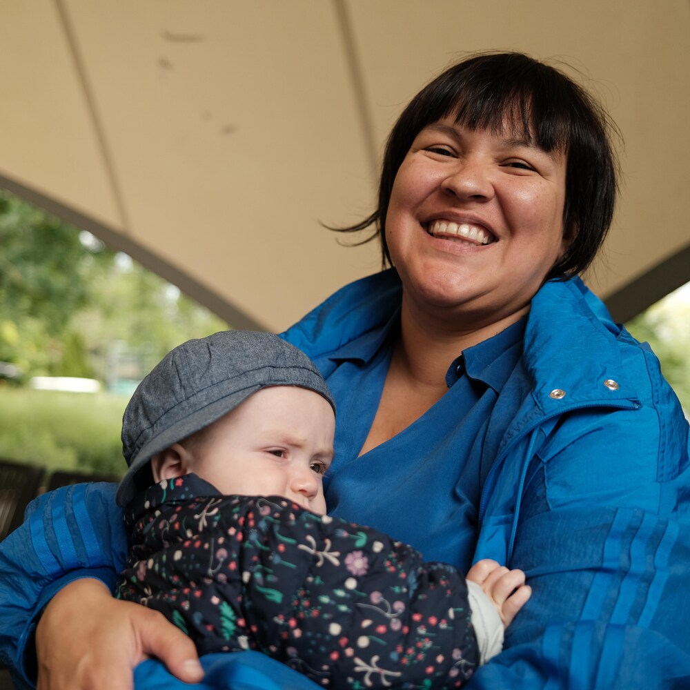 Swaneige Bertrand en train de rire tenant un bébé dans les bras, au Jardin botanique de Montréal, en août 2022.