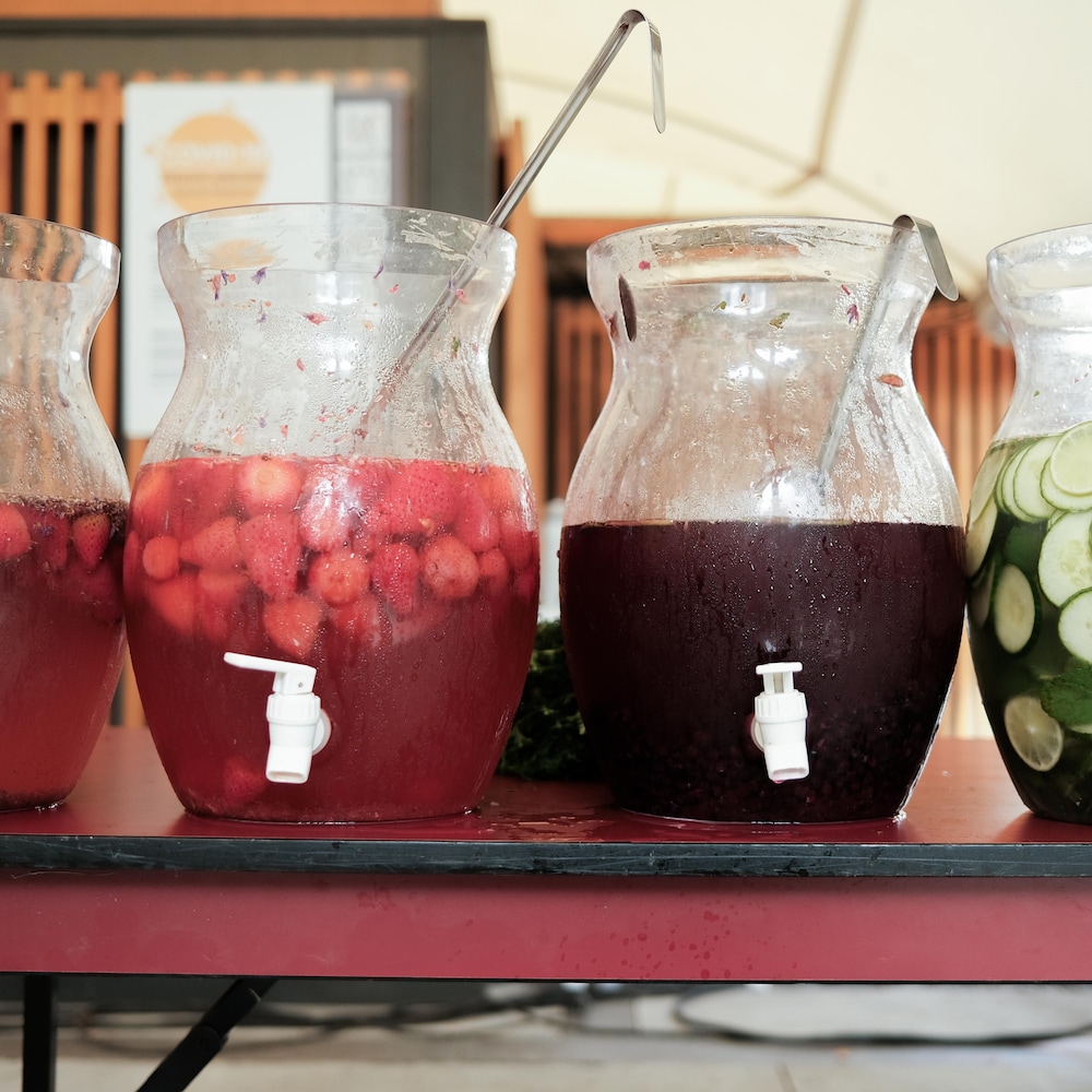 Quatre grandes jarres remplies de thés aux fruits posées sur une table, au Jardin botanique de Montréal, en août 2022.