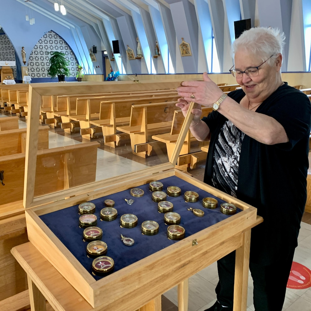 Lina Cormier ouvre le couvercle protecteur pour montrer les reliques d'apôtres exposées dans l'église.