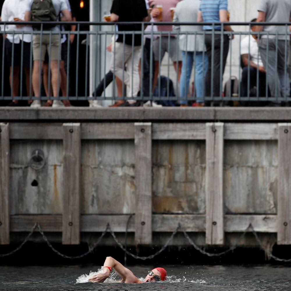 Un nageur dans un canal de Londres surplombé par des passants.