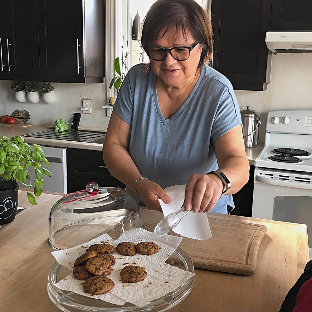 Une femme dans sa cuisine sert des biscuits.