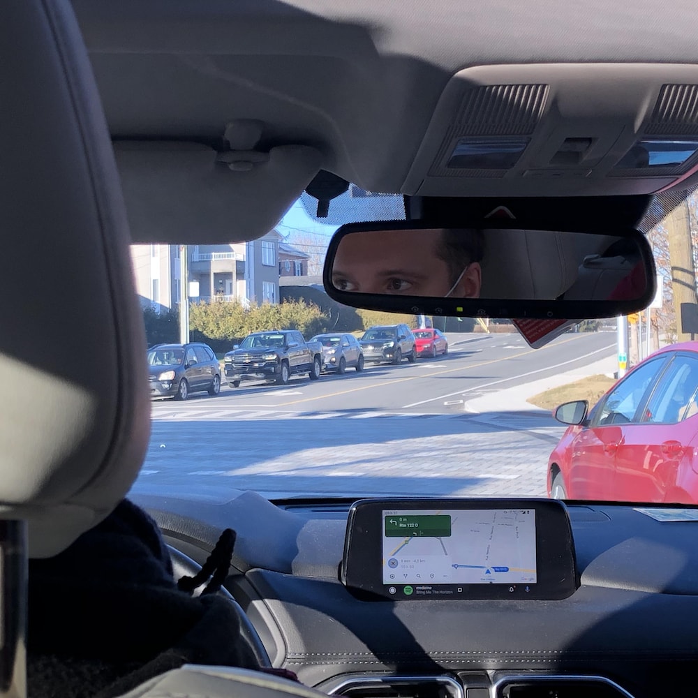 Les yeux d’un homme dans le rétroviseur de sa voiture.