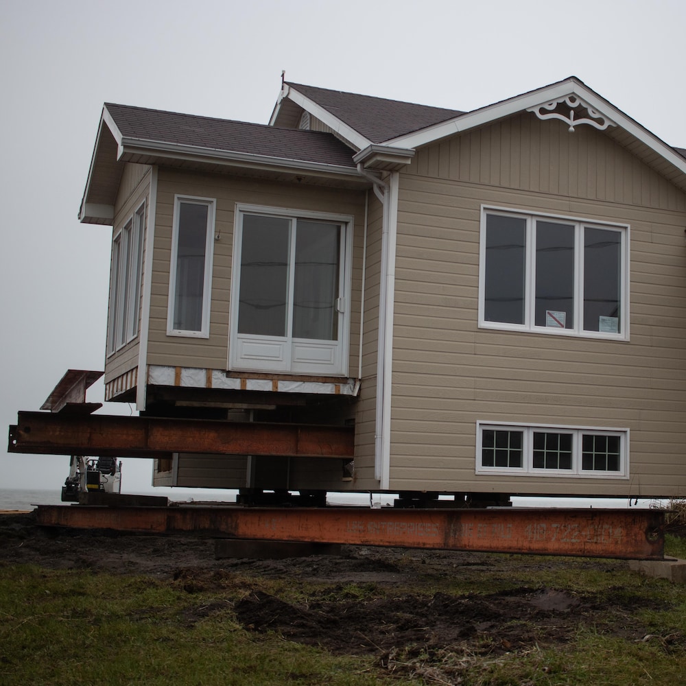 Une maison sur le bord du fleuve est soulevée sur des poutres d'acier.