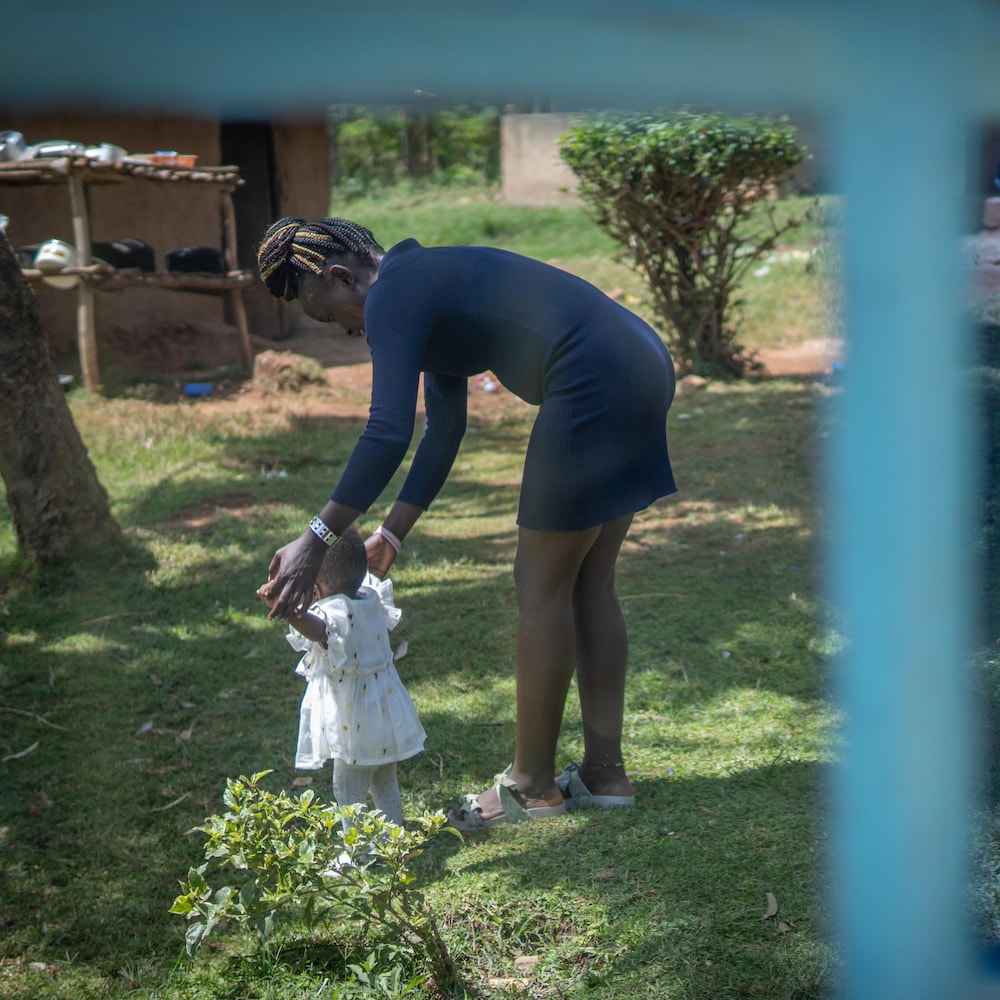 Sarah Onyango marche avec sa fille Ariadne dans un jardin.