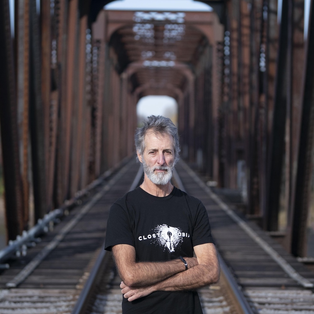 Martin Archambault devant un pont ferroviaire.
