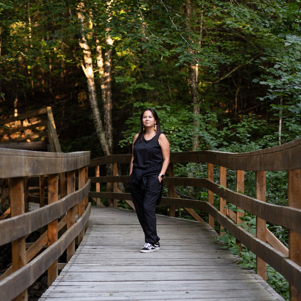 Une femme sur une passerelle en forêt.