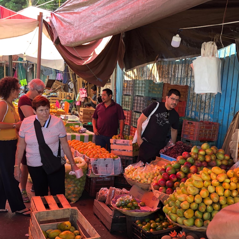 Rodolfo Castellanos et des clients devant un étal de fruits et légumes.