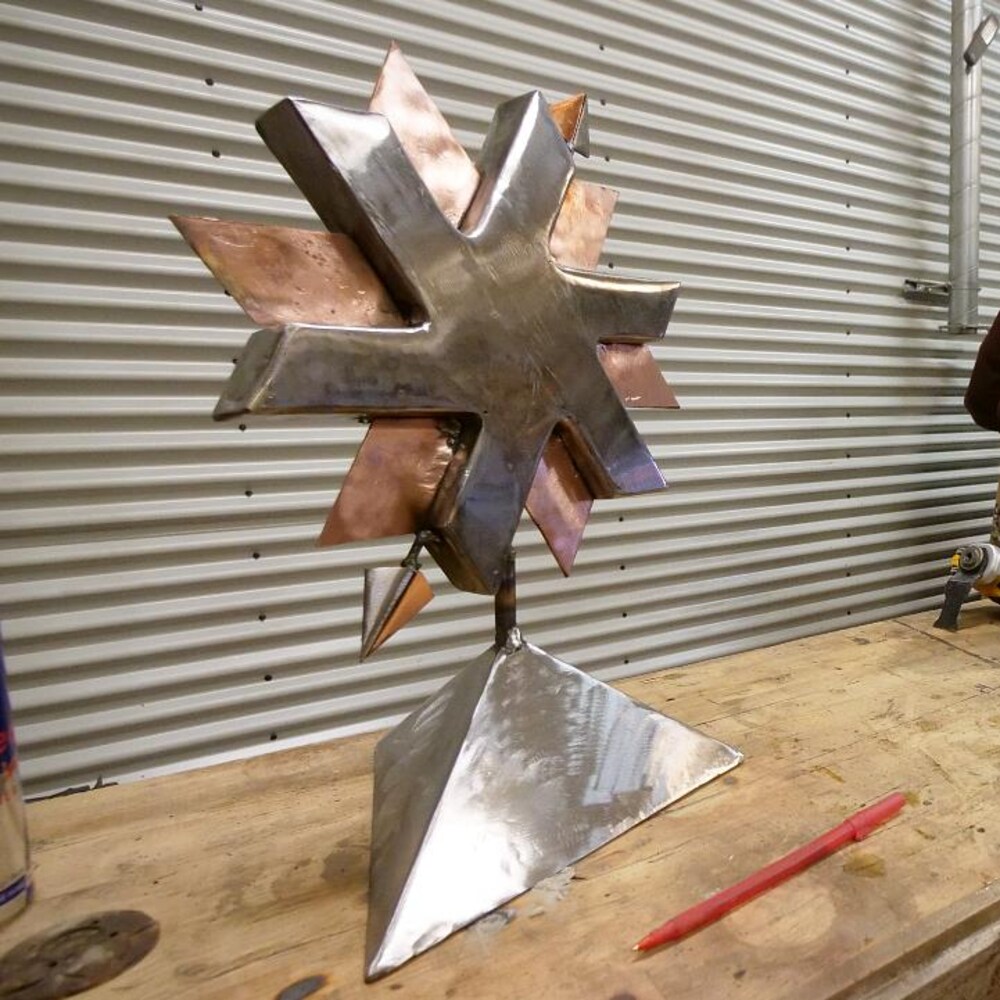 Une sculpture de métal en forme d'étoile polaire est posée sur une table, dans un studio de soudure.