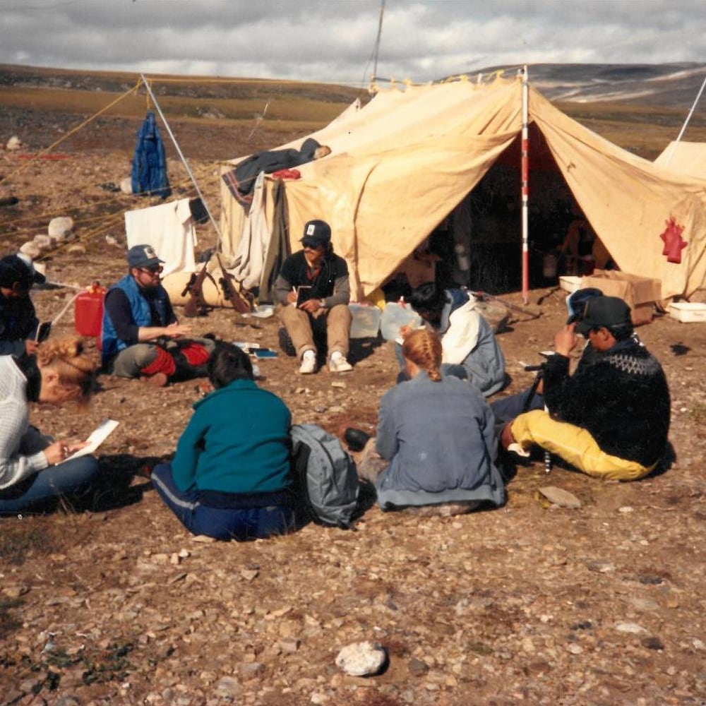 Des étudiants sont assis au sol près d'une tente, à plusieurs kilomètres à l'ouest d'Iqaluit, en septembre 1992