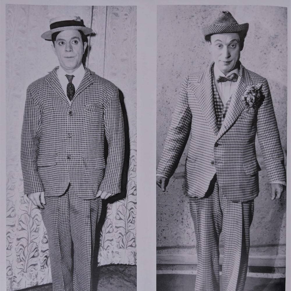 Les deux hommes sont habillés de manière similaire : un complet carotté, des souliers en cuir et un petit chapeau.