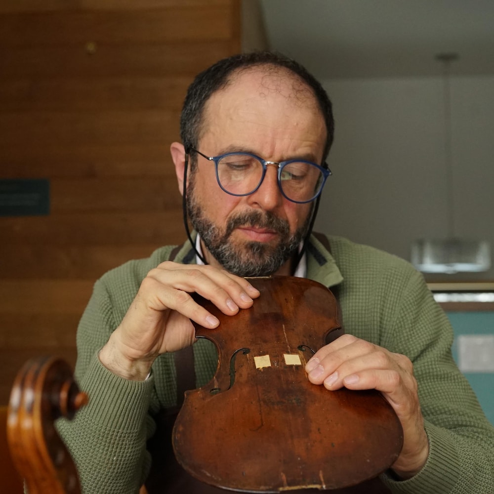 Le luthier examine la pièce qu'il a entre les mains.