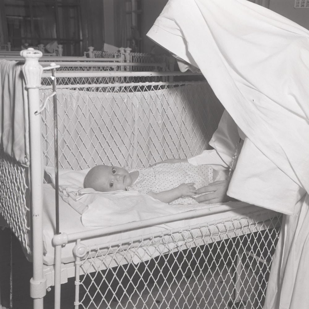 Un nouveau-né entre les mains d'une sœur à l'Orphelinat de Chicoutimi.