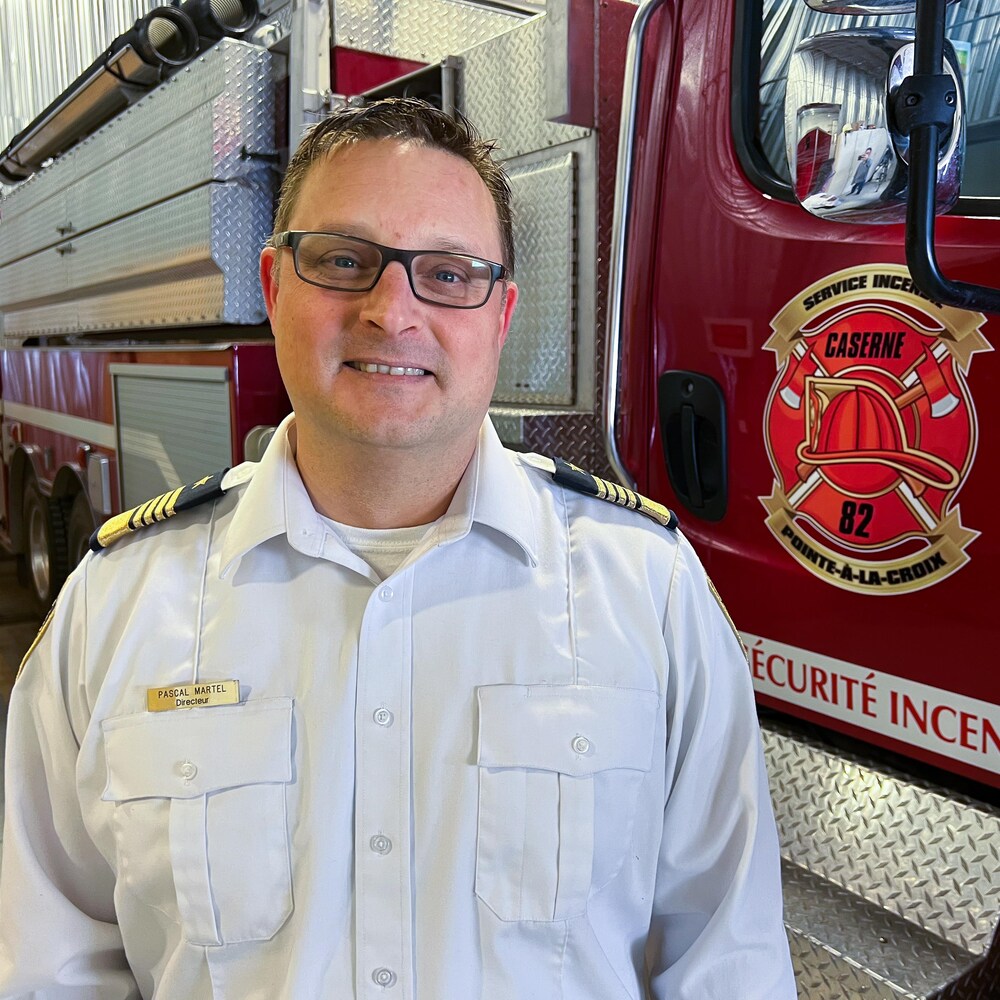 Le chef des pompiers pose devant un camion incendie.