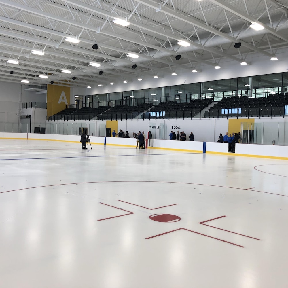 On voit une patinoire intérieure. Elle est aménagée comme les glaces nord-américaines qui accueillent des matchs de hockey.