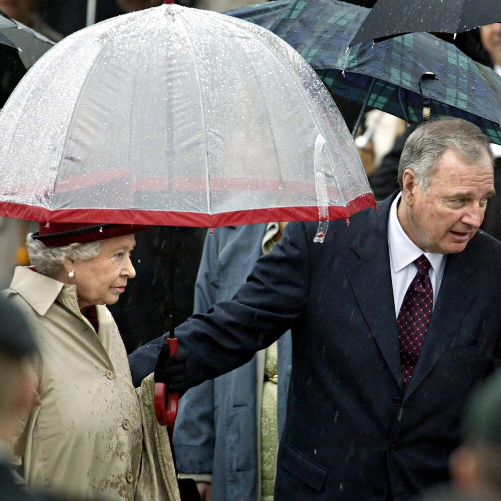 La reine tient un parapluie.
