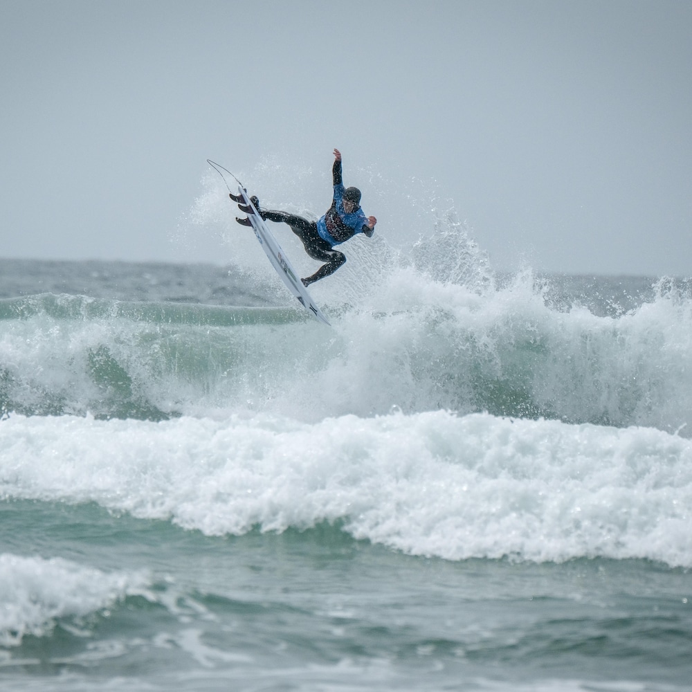 Peter Devries, champion canadien de surf 2019, est debout sur sa planche en haut d'une vague qui se brise à Tofino.