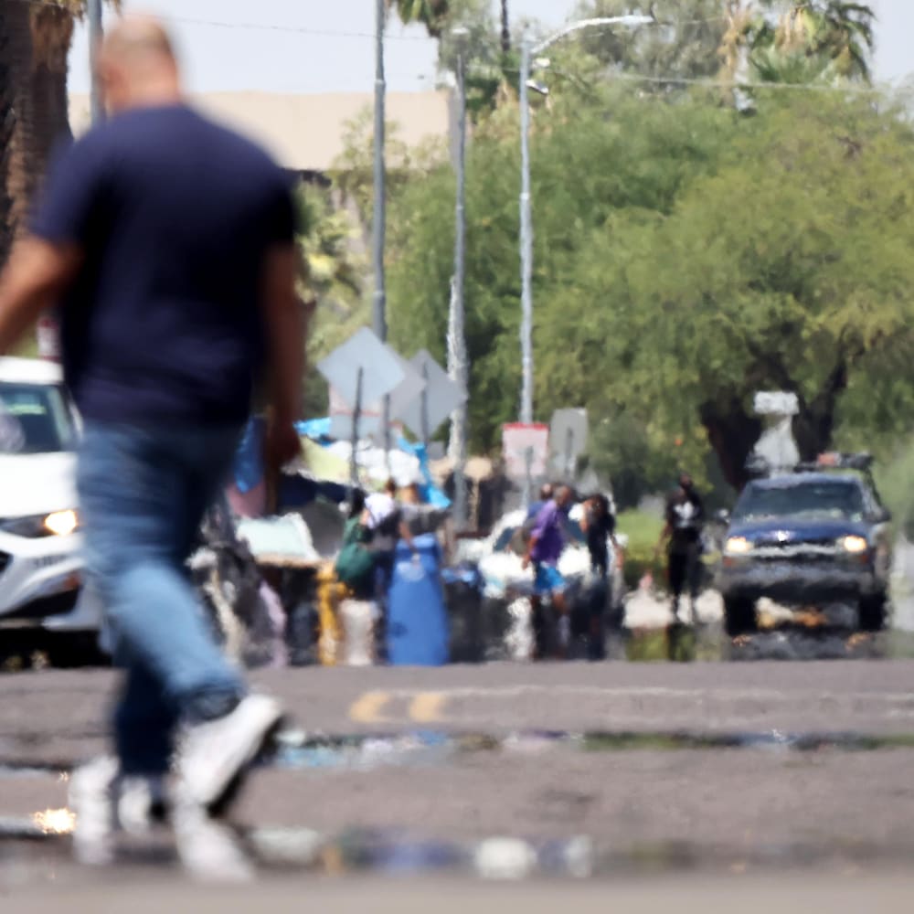 Un homme marche dans une rue asphaltée.