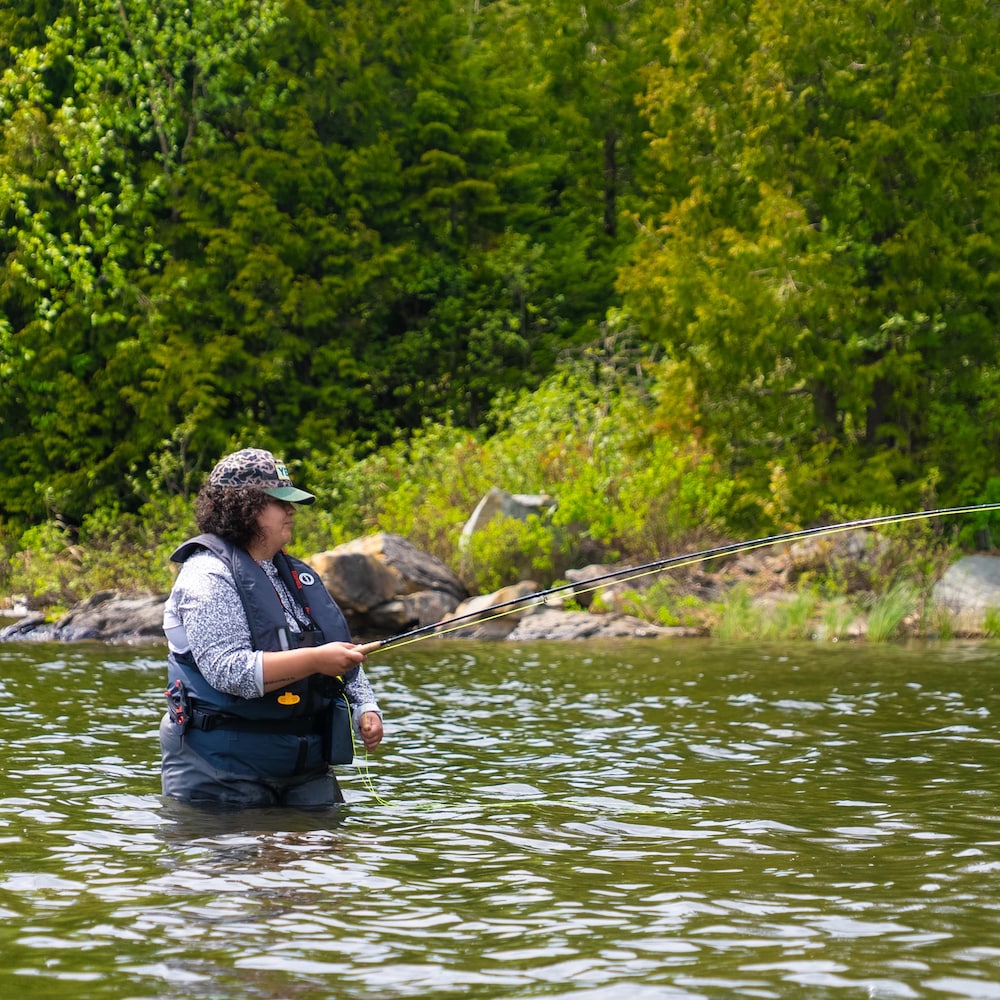 Une femme à la pêche à la mouche dans un lac.
