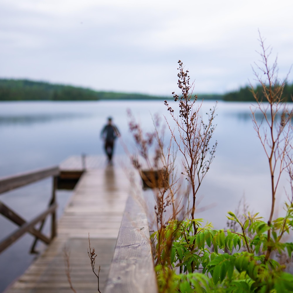 La silhouette d'un homme sur un quai devant un lac.