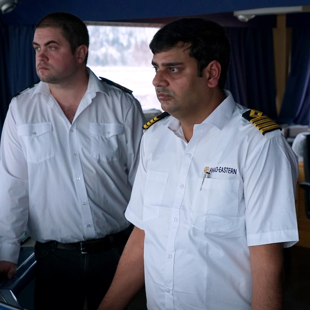 Deux hommes habillés en blanc, dont un capitaine, dans un bateau.