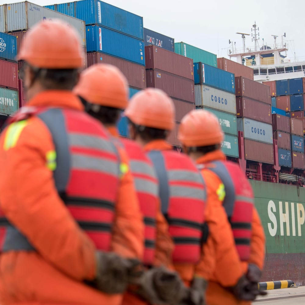 Des travailleurs regardent un cargo s'approcher d'un terminal au port de Qingdao dans le Shandong.