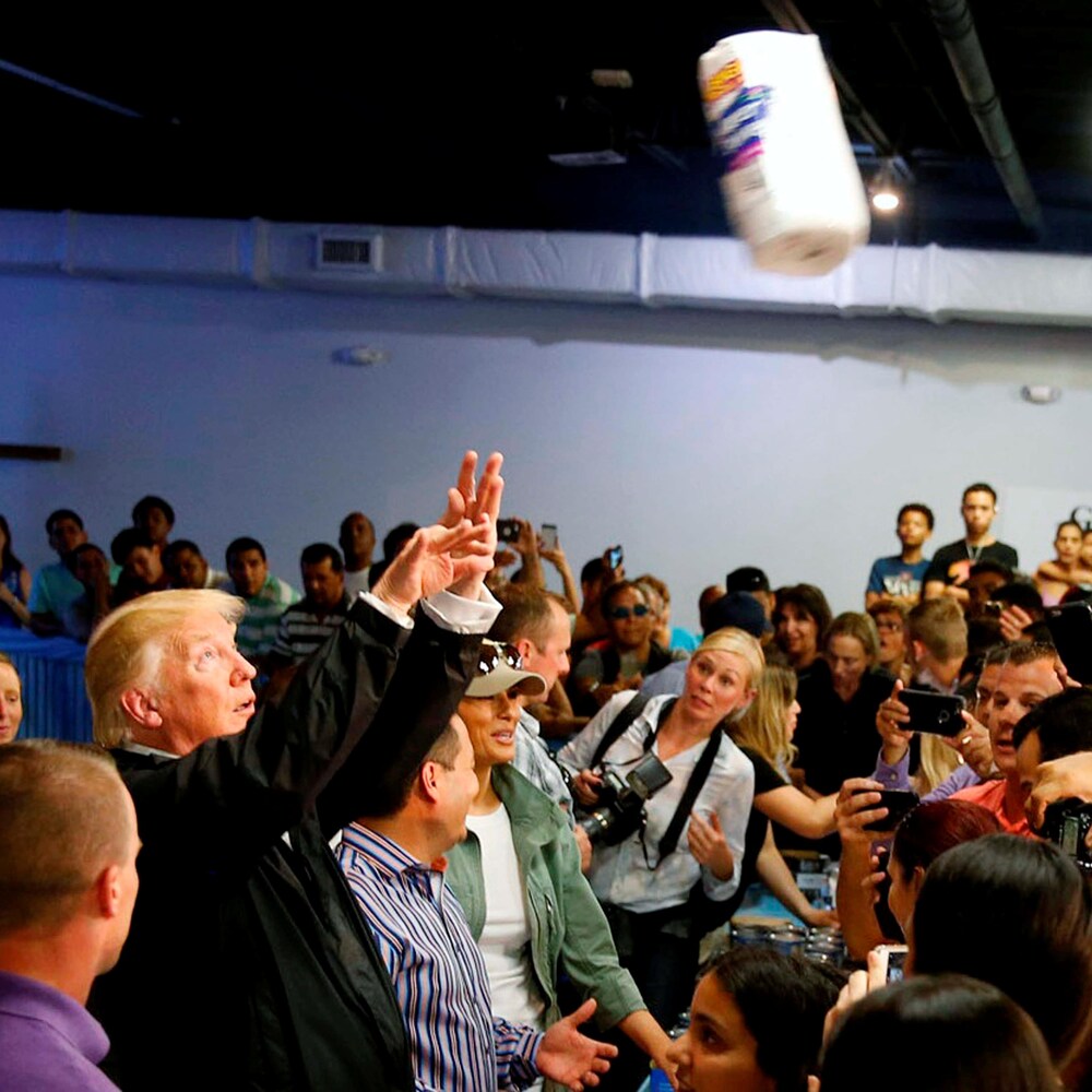 Donald Trump entouré de gens leur lance des rouleaux d'essuie-tout.